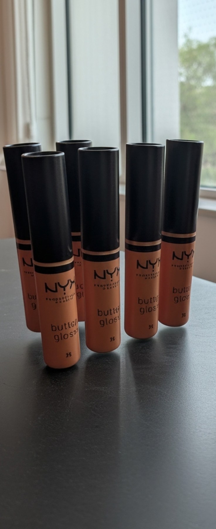 A set of oversized butter gloss makeup bottle props finished and staged in natural light