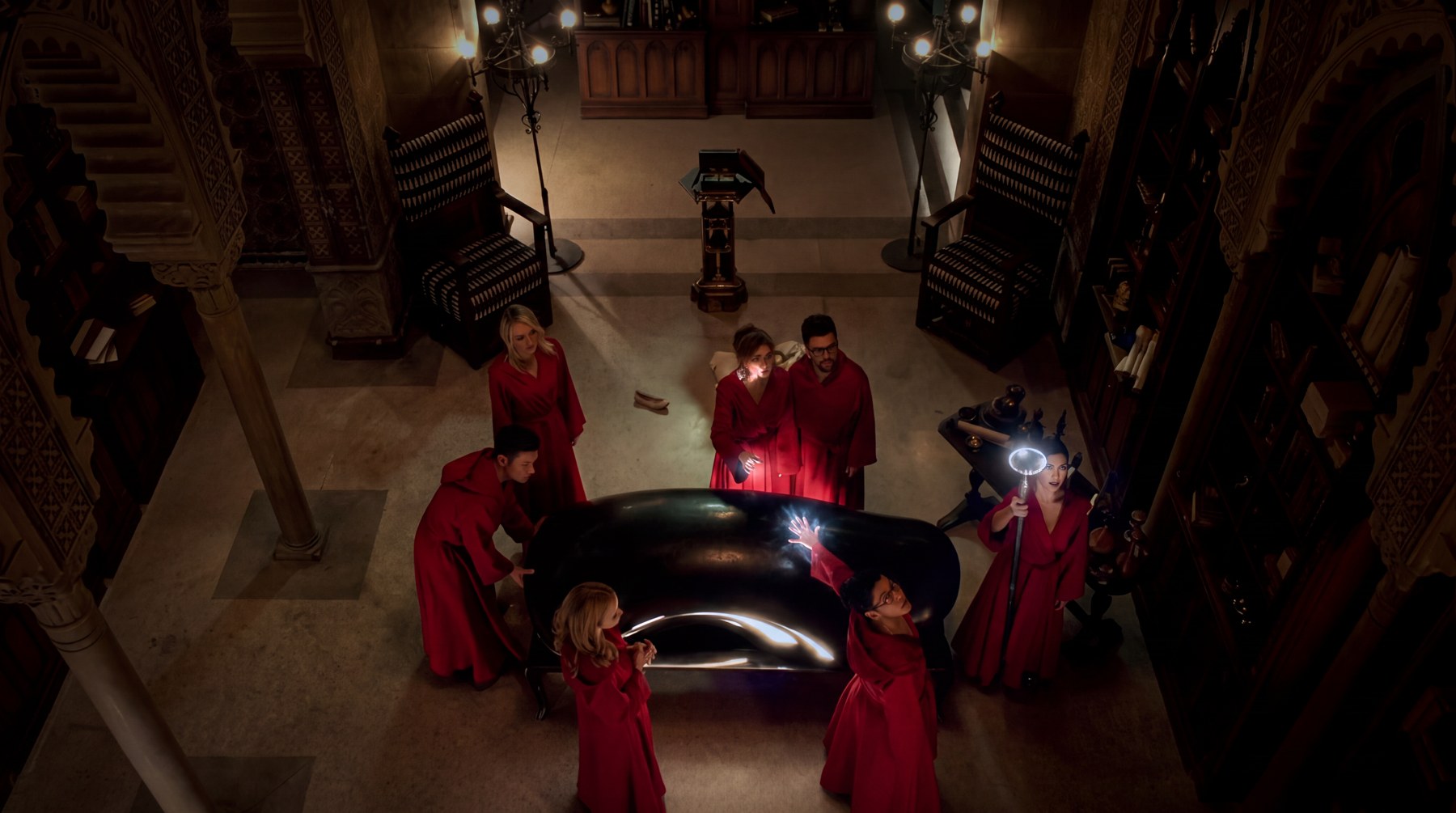 The finished black sarcophagus prop on screen in Marvel's Runaways, surrounded by red robed figures in a gothic library