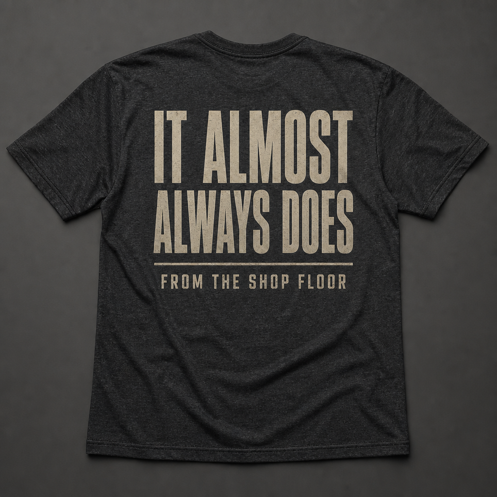 Back of charcoal heather t-shirt reading IT ALMOST ALWAYS DOES and FROM THE SHOP FLOOR