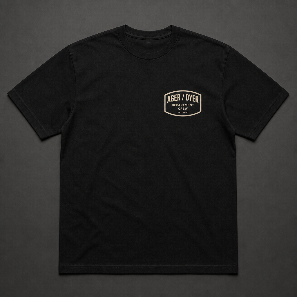 Front of black t-shirt with a left-chest AGER / DYER department badge