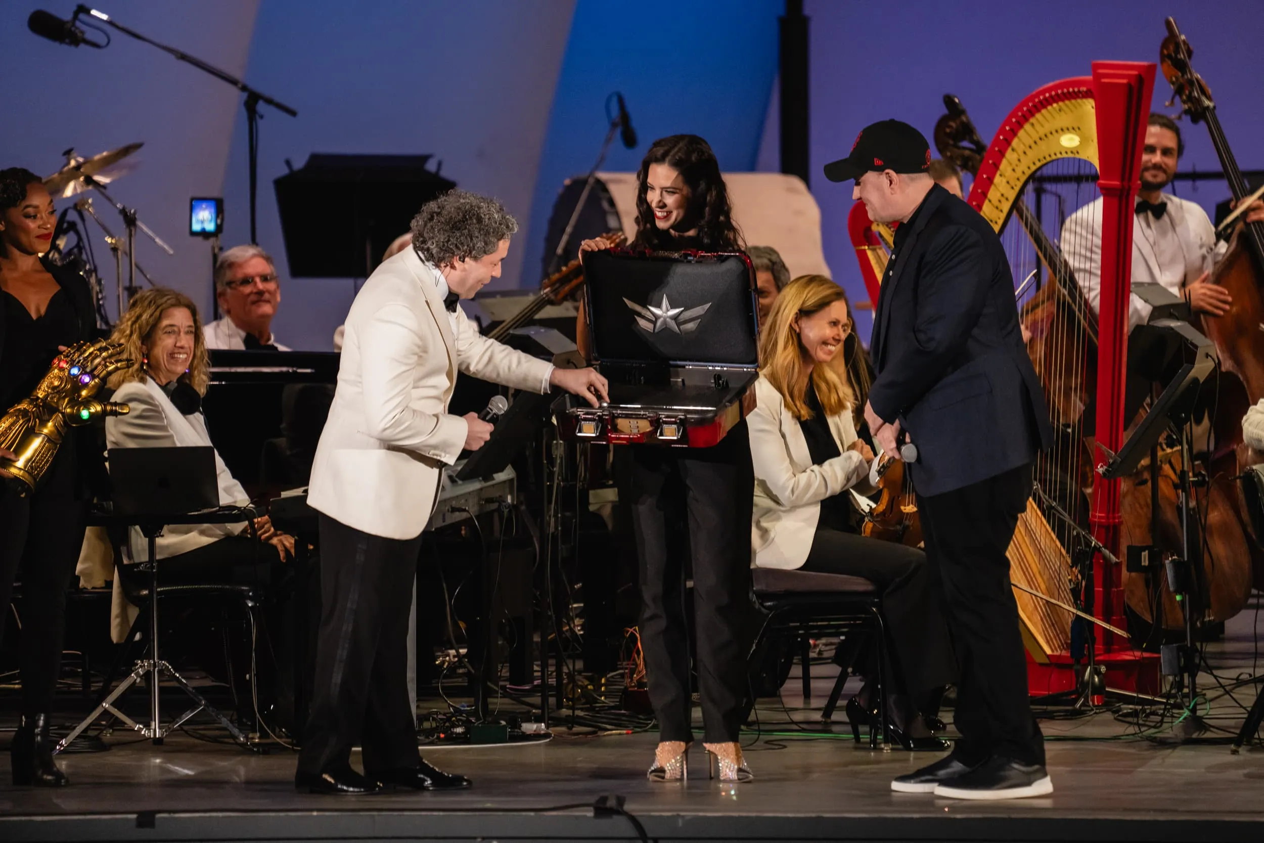 Gustavo Dudamel reaching for the vibranium inspired button on the Iron Man themed case on stage, with Kevin Feige looking on
